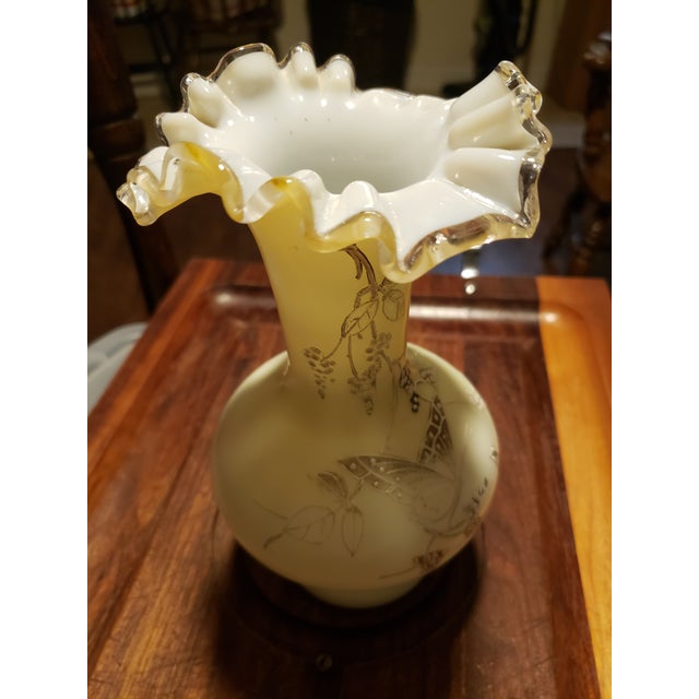 A beautifully hand-blown vintage Fenton Custard Satin glass vase featuring a hand-painted butterfly design with...