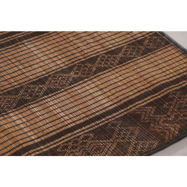 Made with handwoven reed and camel leather in Mauritania circa 1950-1960, this 6x9 vintage Tuareg mat is an exceptional...