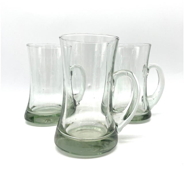 A striking set of three solid glass tankards (handled mugs) from the Mid-Century Modern era (circa 1960s/1970s). The...
