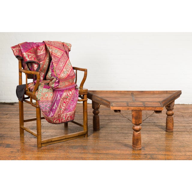 An antique rustic Indian handmade coffee table from the 19th century with trapezoidal top, diamond shaped studs, twisted...