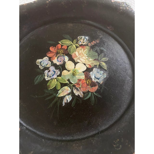 This is a Victorian papier-mâché cake plate or serving tray. It is black and decorated with painted flowers and mother of...