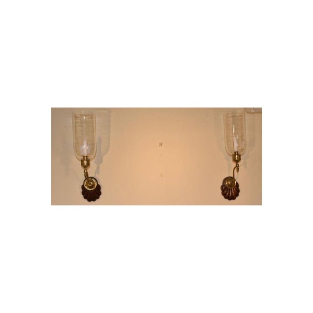 A beautiful pair of Anglo Indian sconces of typical form with arching arms holding glass shades. The sconces are well...