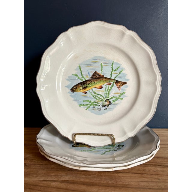 Three French faience plates from the "Indre" fish service by Sarreguemines, each decorated with a different freshwater...