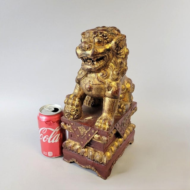 A richly carved giltwood guardian lion, circa 1900, originally part of a Chinese temple or architectural panel. The lion...