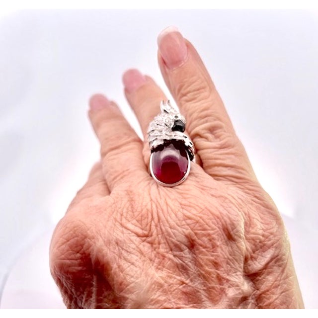 This extraordinary cocktail ring is a true work of wearable art, showcasing a magnificent large oval ruby cabochon 8 to 10...