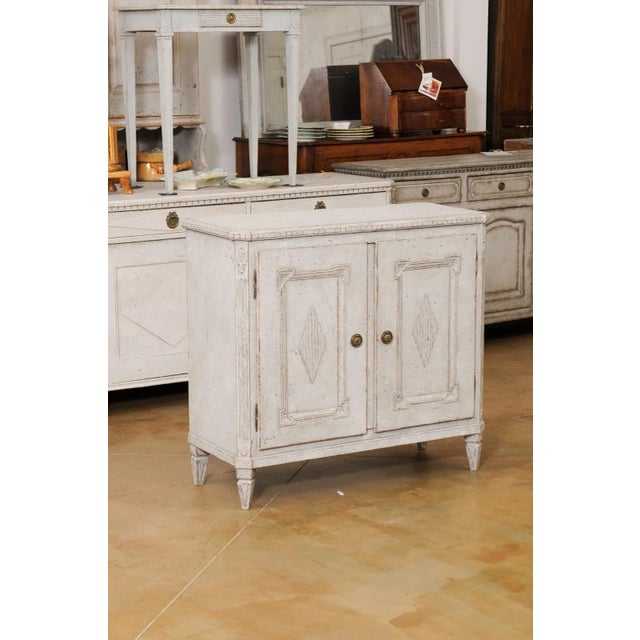 A Swedish Gustavian style painted wood sideboard from the late 19th century, with diamond motifs and carved rosettes....