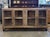 Rustic buffet built from salvaged barn wood, with deeply textured grain and a weathered, sun-faded finish. Four glass-...