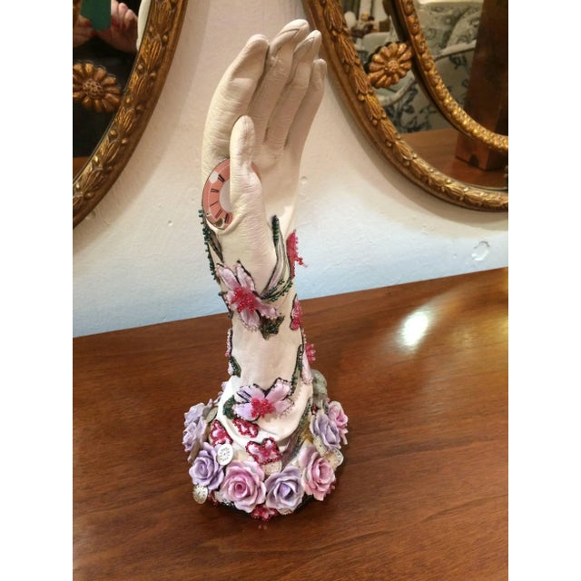 Mixed-media thoughtful assemblage sculpture of a leather gloved hand embellished with porcelain flowers, floral beaded...