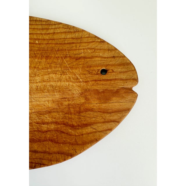 Mid-20th-century, handmade wooden cutting board featuring a fish shape and eye cutout. Perfect size for a small cutting or...