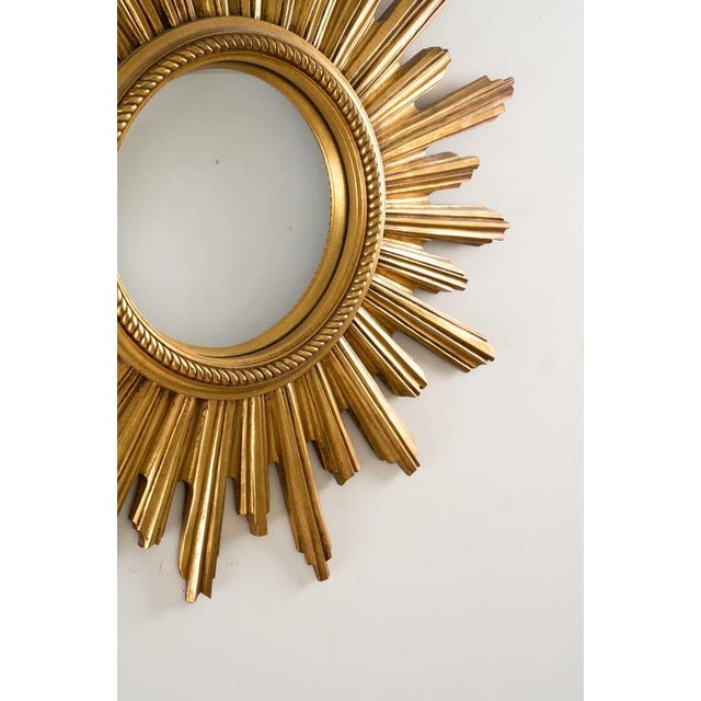 This vintage mid-century modern convex sunburst wall mirror is a classic example of the Hollywood Regency style. Crafted...