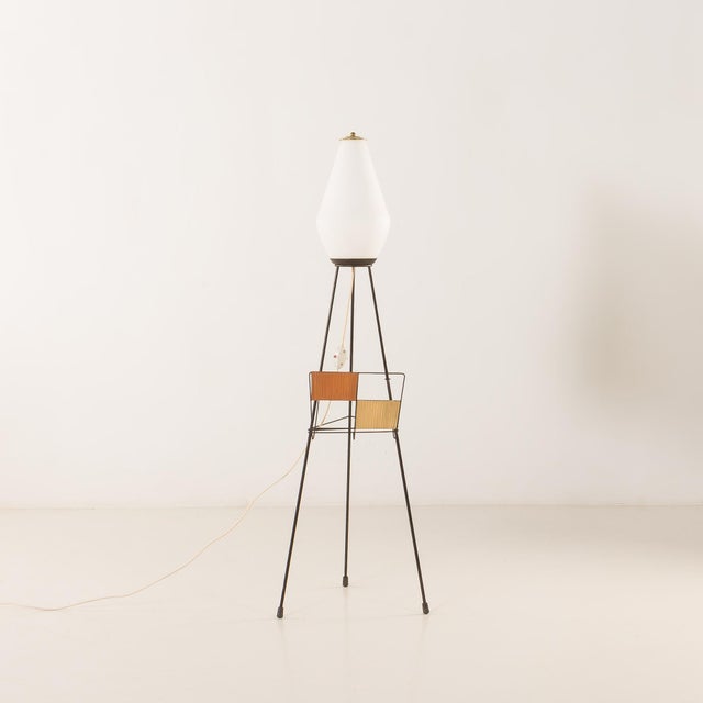 This italian mid-century floor lamp with a newspaper rack, from the 1960s, is a functional and stylish example of postwar...
