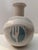 A striking handcrafted ceramic vessel featuring a rounded body and flared neck, adorned with textured relief patterns and...