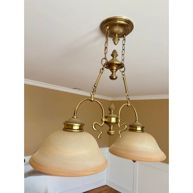 This classic dual-light pendant chandelier features an elegant, traditional design crafted from solid brass with a...
