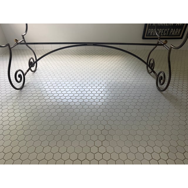 Striking custom vintage dining table featuring an elegant black wrought iron scroll base with a sculptural silhouette and...