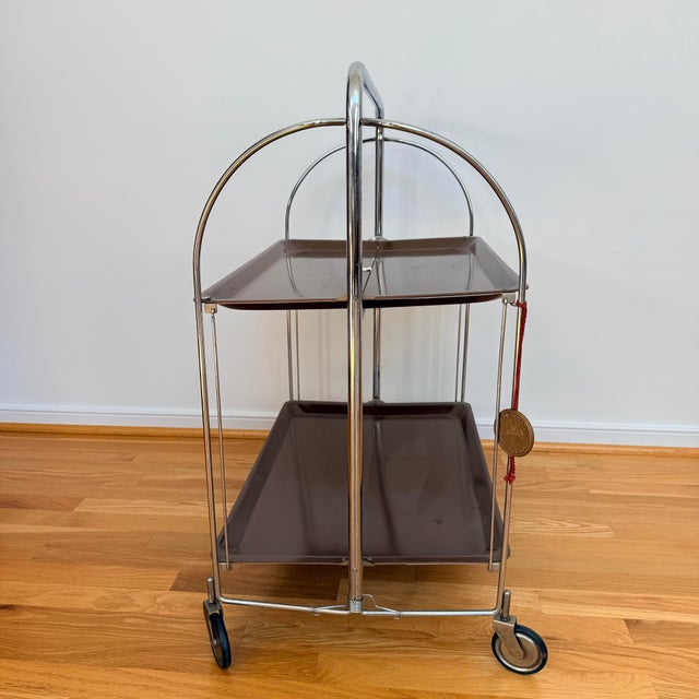 A wonderful example of 1970s German design, this vintage Bremshey folding bar cart combines sleek chrome tubing with two...
