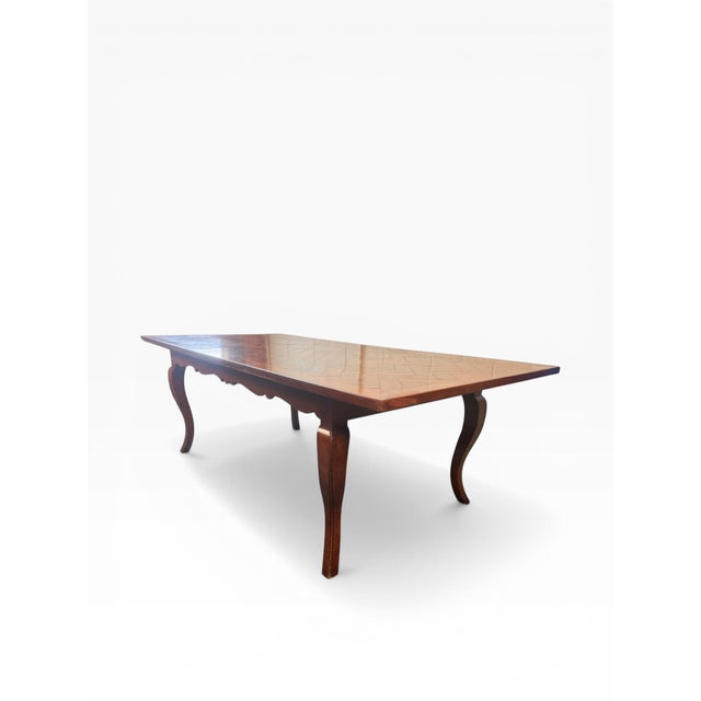 A striking farmhouse dining table defined by its richly patterned parquet top and graceful cabriole legs—bringing together...