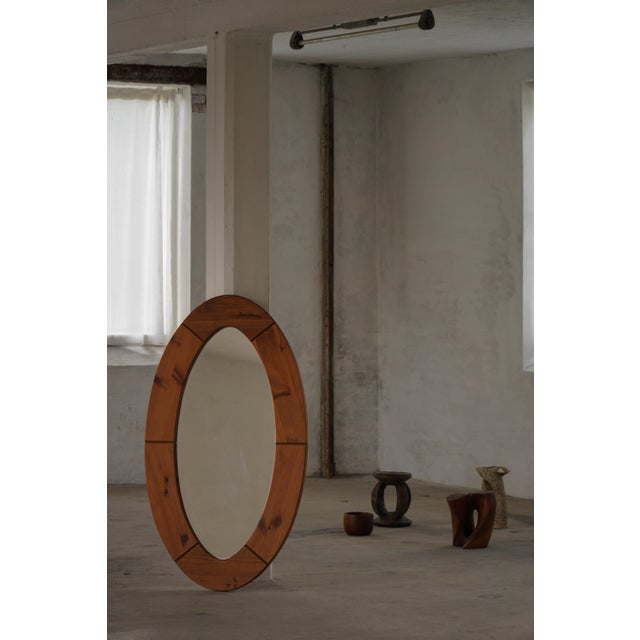 This sculptural wall mirror was crafted in Sweden during the 1960s by Glasmäster Markaryd and features a broad, rounded...
