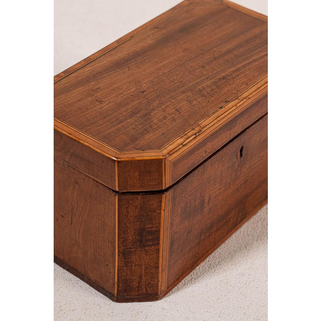 19th-century English mahogany tea caddy with satinwood inlay, hinged lid, and intact interior compartments.