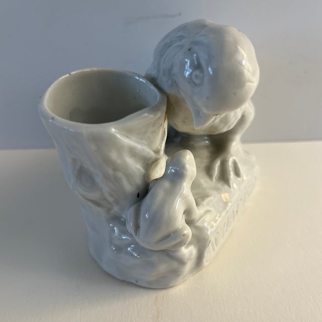 Very charming antique English match holder and striker, says "What is It," on the bottom edge. It portrays a chick looking...