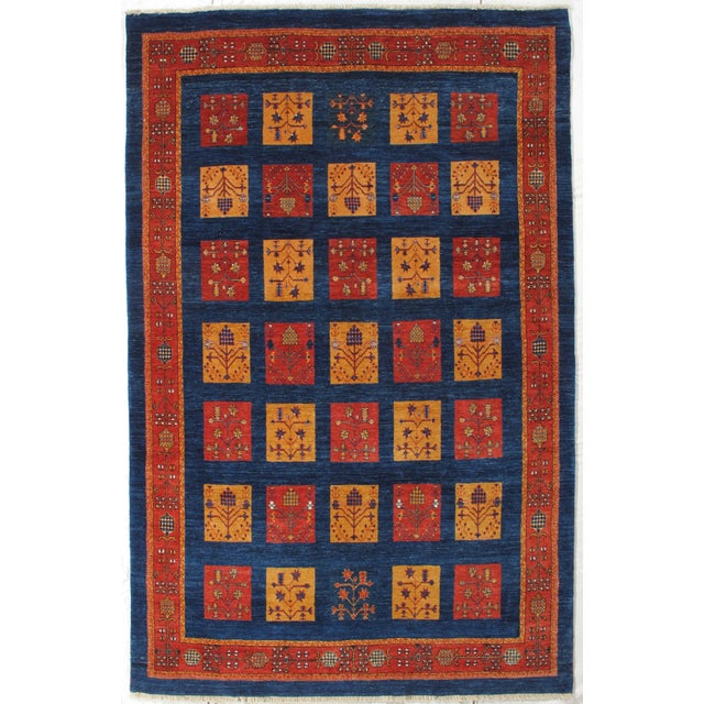 Vintage Hand-knotted Persian Lori Gabbeh rug featuring a deep indigo field with a grid of alternating red and gold...