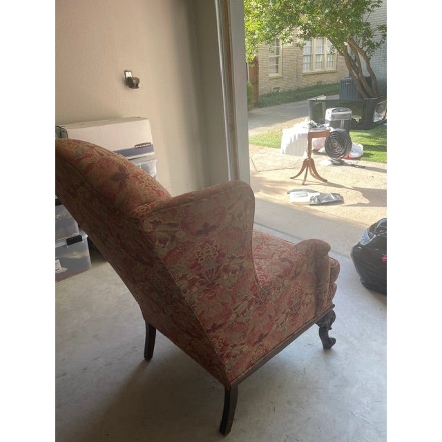 Wingback fireside chair features a classic Chippendale style. The chair is upholstered in red, gold and lighter gold/beige...