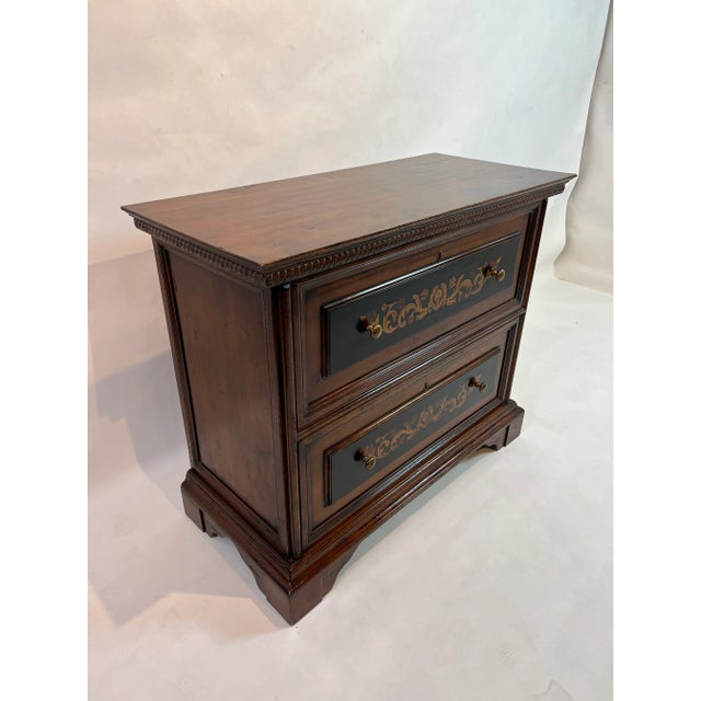 Carved two drawer walnut chest with inlaid floral motif on an ebony background, accented with brass hardware. Italy.