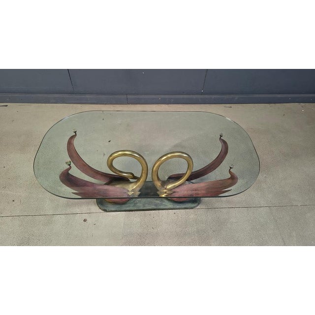 Elegant coffee table with a double swan base in brass with their curled necks. Their wings serve as the table top...