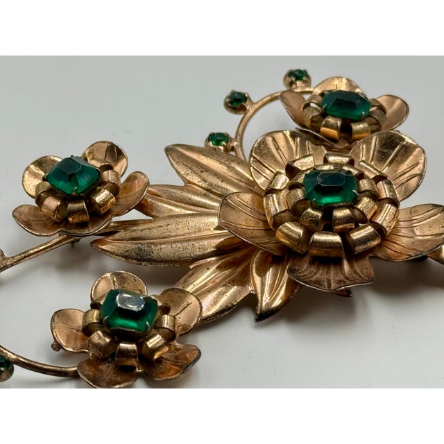 Large 1940s sterling silver brooch with gold vermeil overlay. Floral theme with 10 green rhinestones. The back is stamped...