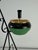 Floor-standing ashtray with magazine rack in enameled wrought iron, 1950s The ashtray features a green and gold finish....