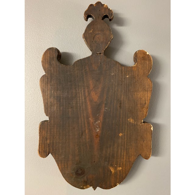 Heraldic wall plaque of rampart lion on oxblood shield, on a gold base.