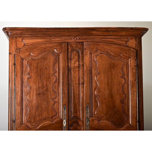 Louis XV period (18th century) French solid walnut armoire with stylized carvings that trace the dramatic paneled doors...