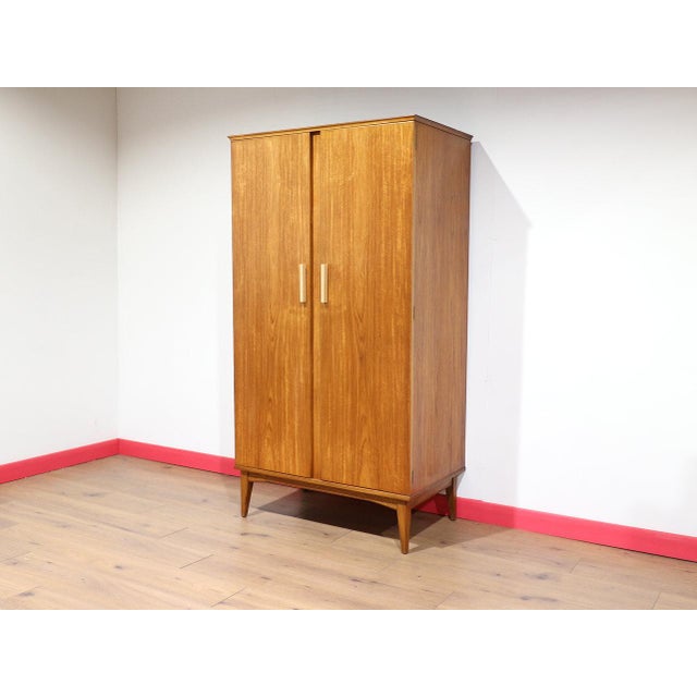 A stunning wardrobe by renowned British furniture maker Alfred Cox, this Mid Century Modern Teak Wardrobe Armoire...