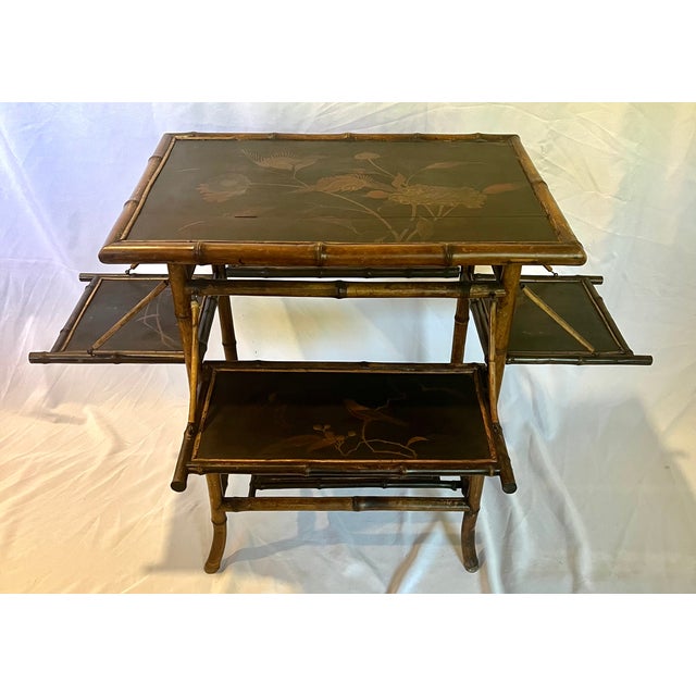 Late 1800s British scorched bamboo tea table. Four collapsible trays each with a hand painted bird and floral design. The...