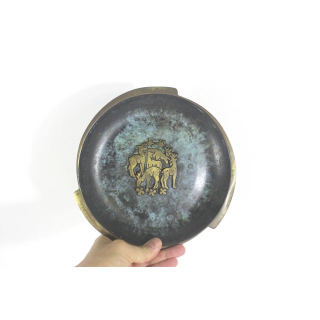 Small brass mid century modern plate with a verdigris patina on the interior and a group of raised brass deer in the...