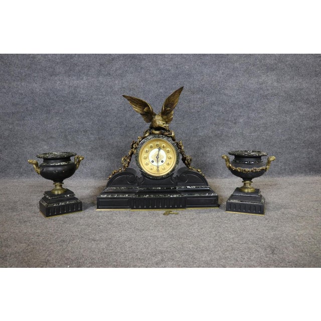 This impressive three-piece marble and bronze clock garniture set is a commanding example of classical decorative arts,...