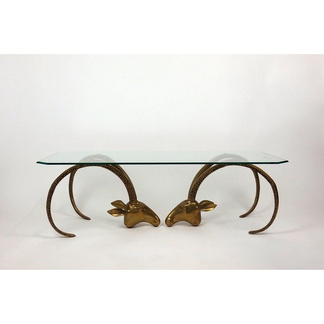 Coffee table made up of two ibex heads whose horns form the base and support a rectangular beveled glass top cut at the...