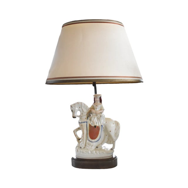 An antique Staffordshire figurine of a woman holding a lamb and riding a horse, with a c.1940s lamp conversion. Very good...