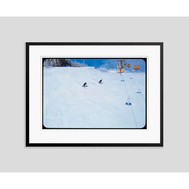 Downhill Racers 1955 Two skiers on a piste go under a ski lift at the Stowe Mountain resort, Vermont, USA, (Toni Frissell)...