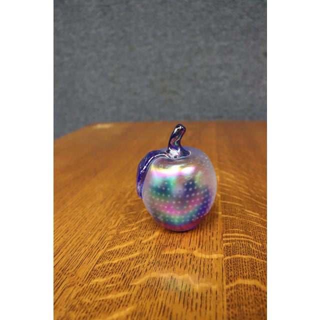 Hand-blown art glass apple featuring a frosted iridescent finish with controlled bubble decoration and a cobalt blue stem...