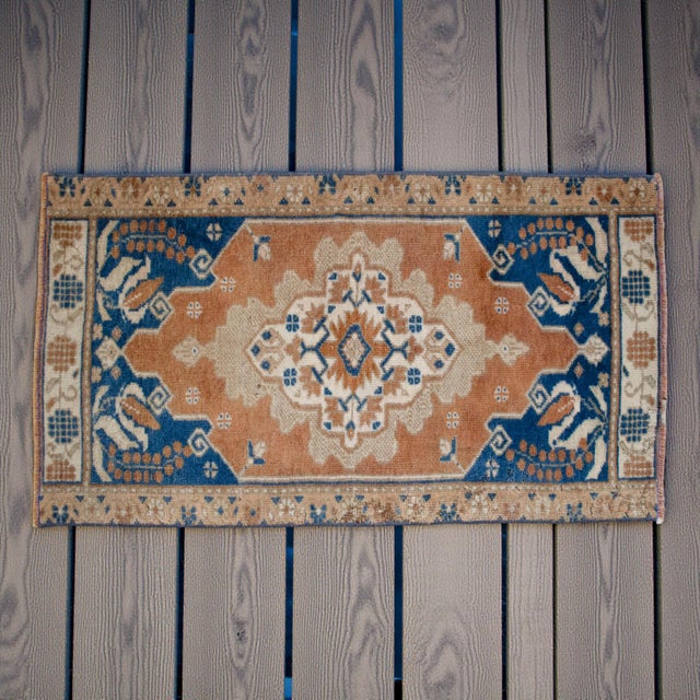 This charming vintage accent rug features a striking central medallion surrounded by earthy terracotta and deep navy blue...