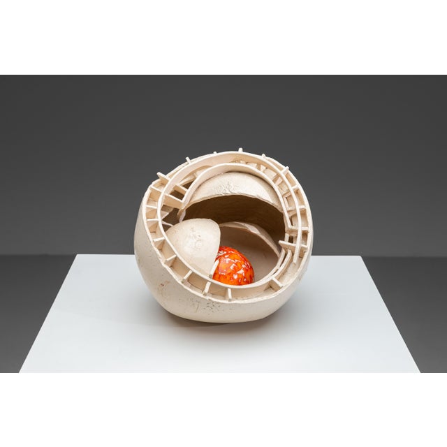 A handmade ceramic sculpture consisting of a large, open shell-like form with layered circular structures and an exposed...