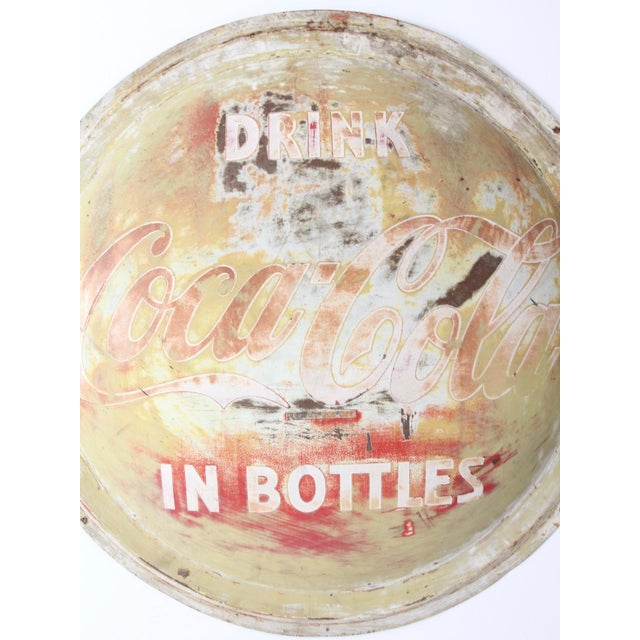 Wearing its original, now wonderfully variegated painted surface, this 1940s Coca-Cola button sign still displays its "...