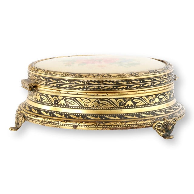 A charming English vanity powder box featuring an elegant gilt metal case with richly engraved decoration and a delicate...