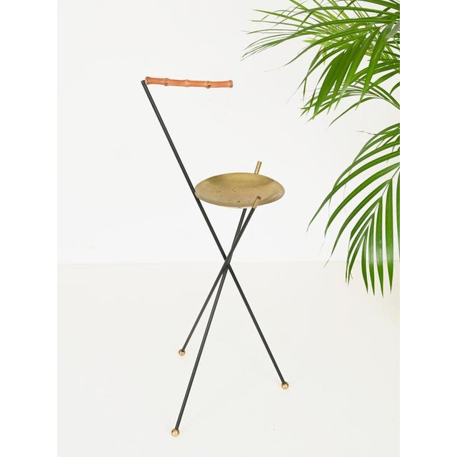 Elegant and unique Italian tripod floor ashtray crafted in black enameled iron, brass, and bamboo. This incredibly stylish...