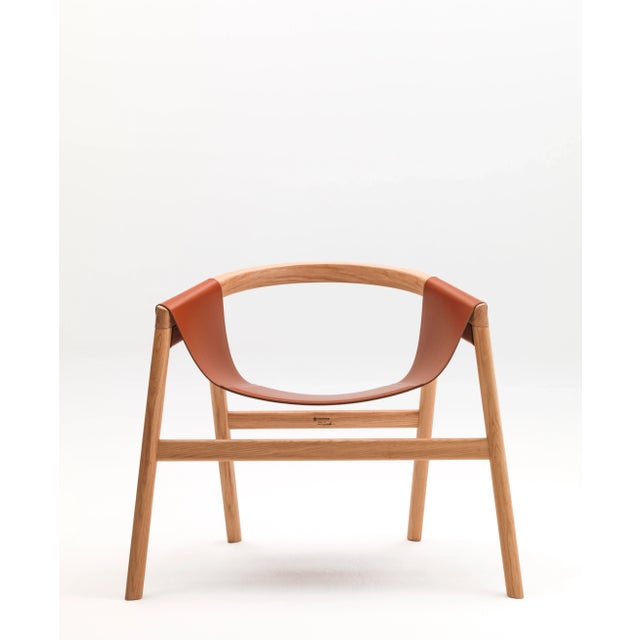 This armchair has an oak structure with saddle leather seat. This piece comes in natural oak or black tinted oak -.