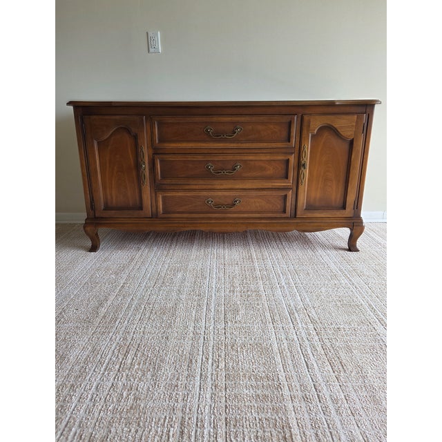 This is a lovely French provincial walnut-finish sideboard from renowned furniture company Drexel, crafted in the mid-20th...