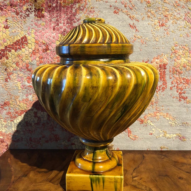 Handpainted ceramic urn in ochre with green accents, featuring a fluted swirl design. Italy.