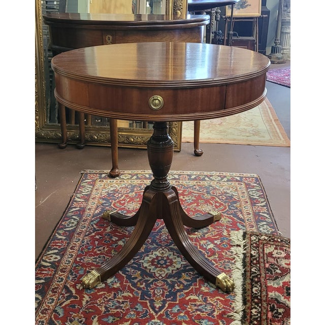 Fine 1940s mahogany empire style drum table. Features well detailed brass lion paw feet, round circular brass pulls with...