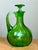 This vintage glass decanter presents a vibrant green hue with a smooth, glossy finish, its bulbous body gracefully...