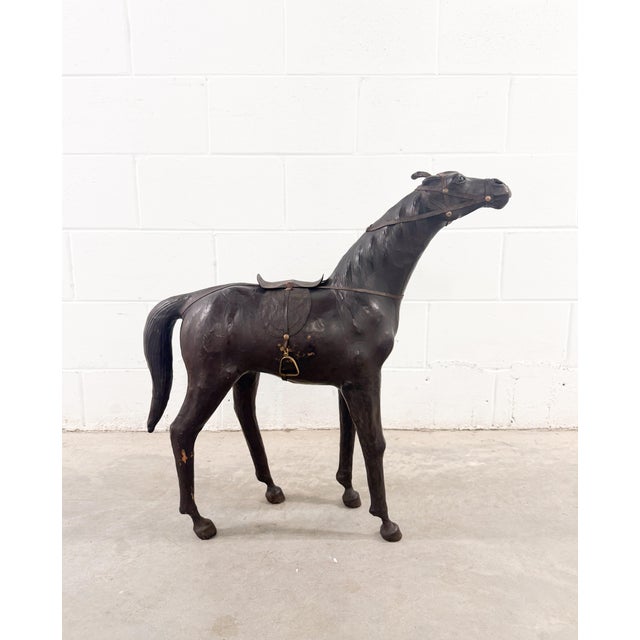 Exquisite mid-century sculptural horse, artfully wrapped in leather, complete with a saddle, bridle, and brass stirrups....
